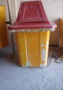 Yellow fiberglass waste basket with a red lid