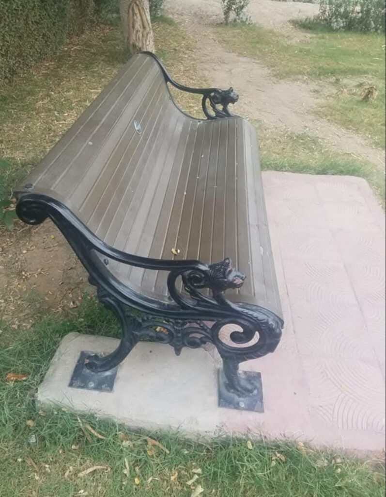 Decorative outdoor bench with brown seating slats and ornate black metal-style supports
