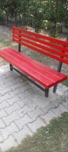 Red outdoor bench with backrest and dark support frame in a garden